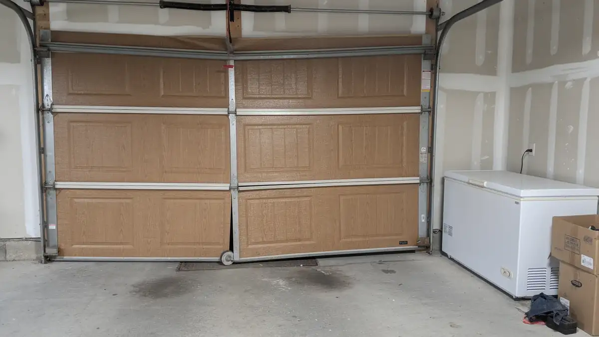 The brown garage door is off its track on the left side.